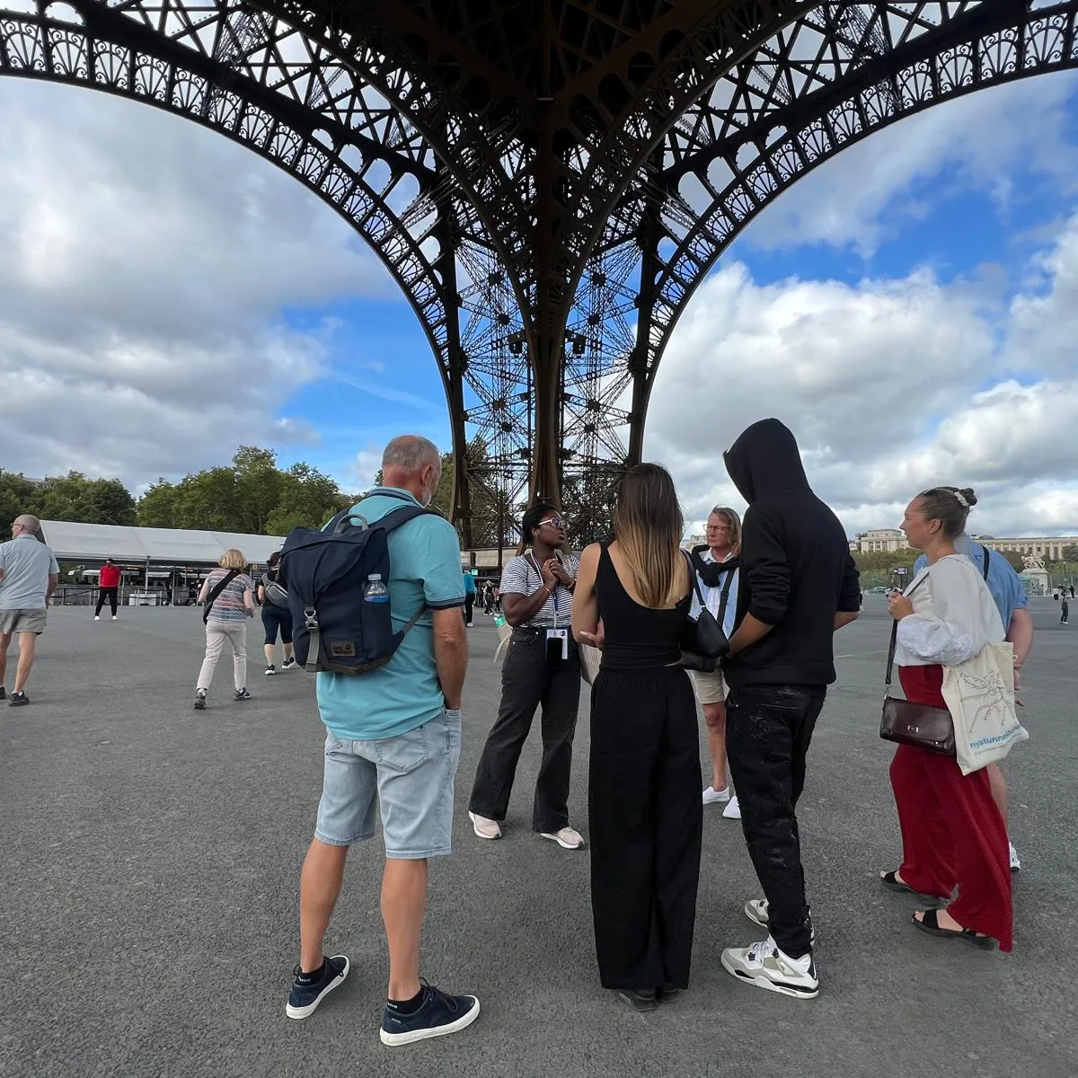 A small group with their tour guide under the Eiffel Tower